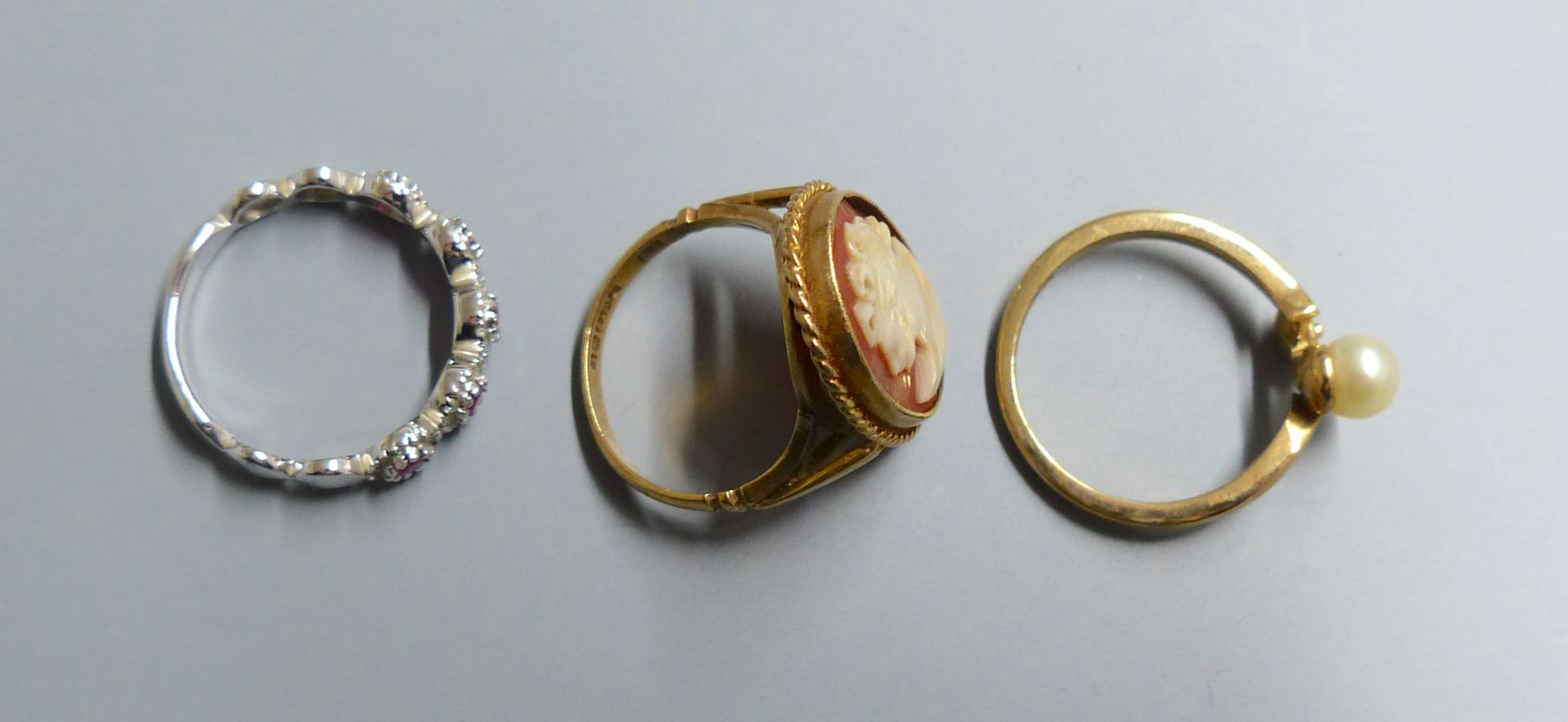 A white gold, ruby and diamond chip five cluster ring, a cameo ring and a pearl set ring